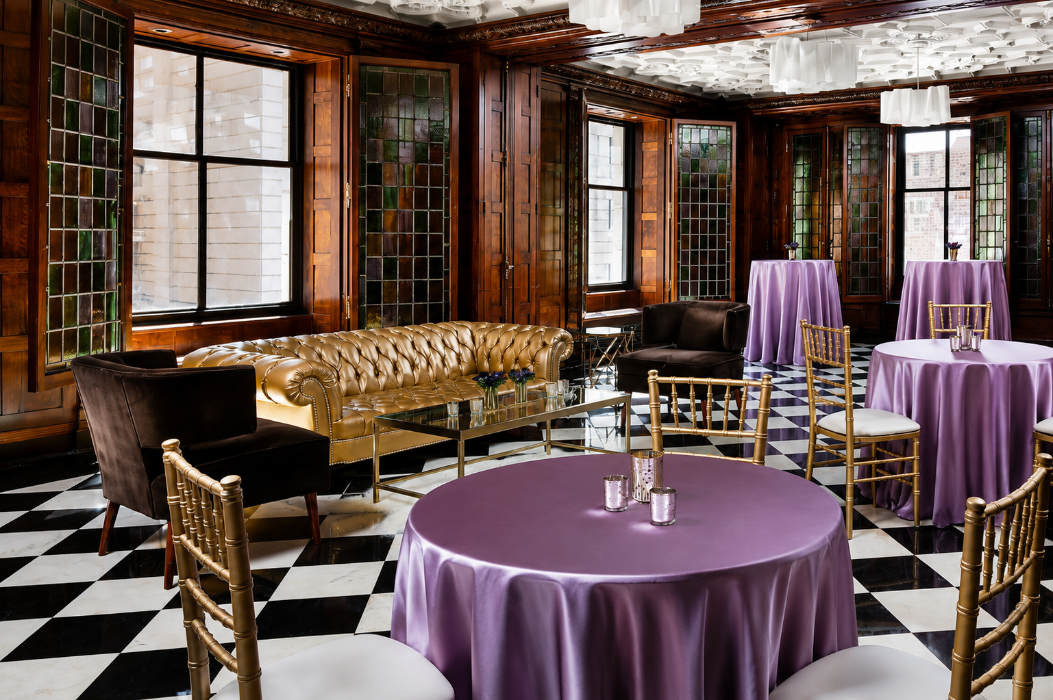 Elegant interior with black and white checkered floor, gold and black chairs, purple tablecloths, a mustard-colored leather sofa, dark wood-paneled walls with stained glass windows, and modern white pendant lights.