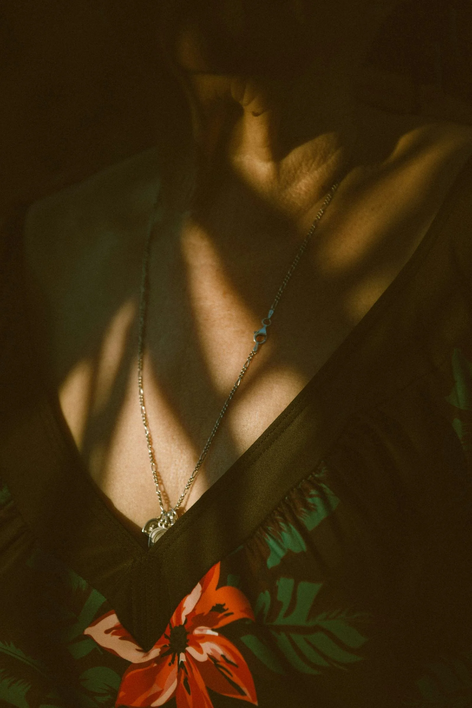 Person wearing a black shirt with a tiger graphic, necklaces, and jewelry, with a dark background.