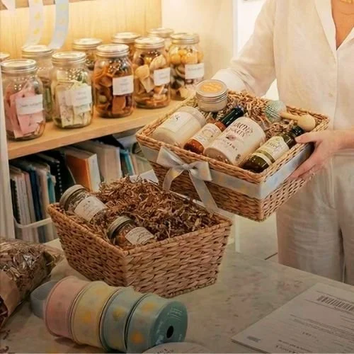 Person holding a basket filled with skincare or beauty products inside a store.