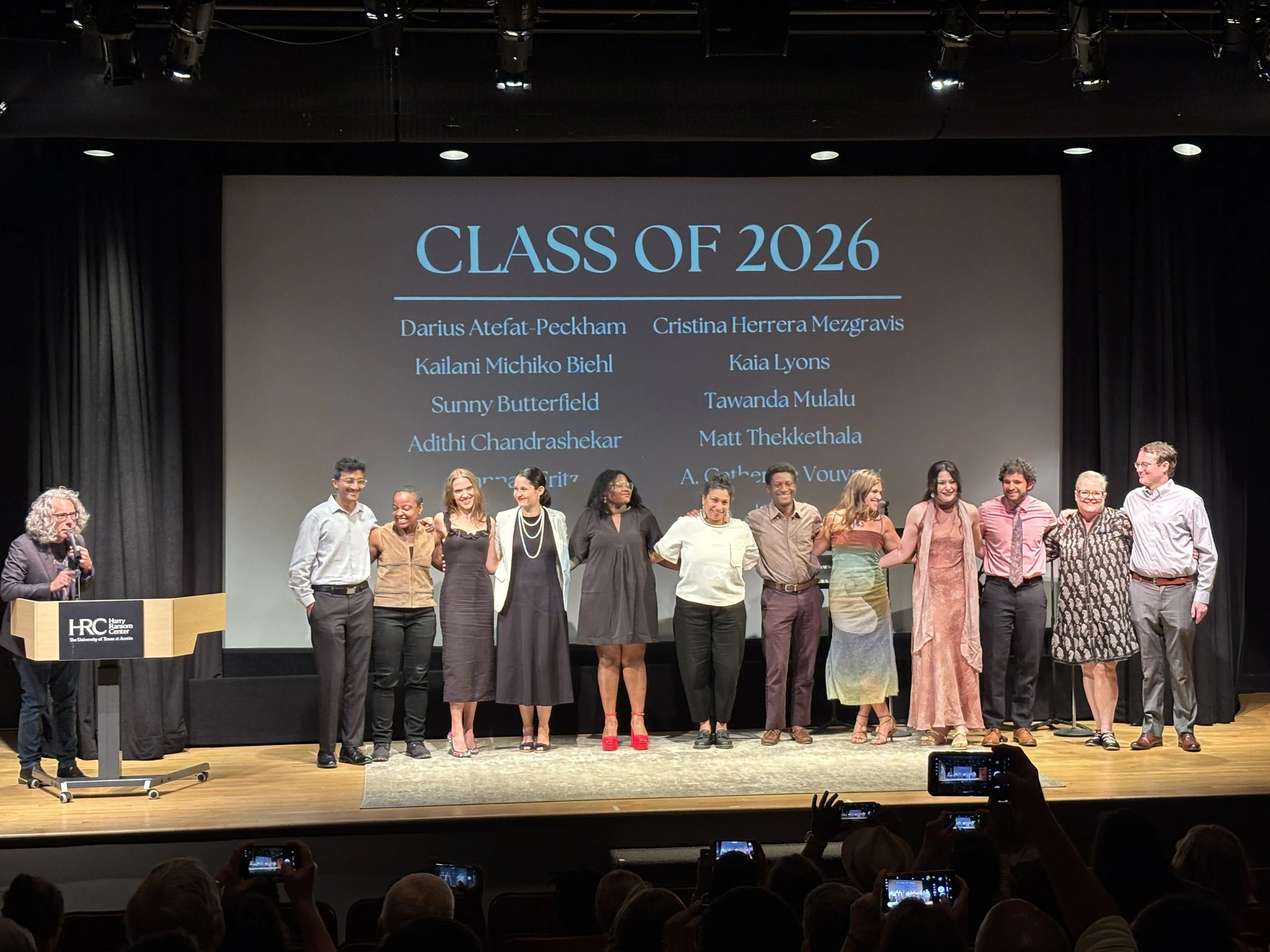 Bret Anthony Johnston at podium with the 12 cohort members in front of the screen with our names and the Michener logo.