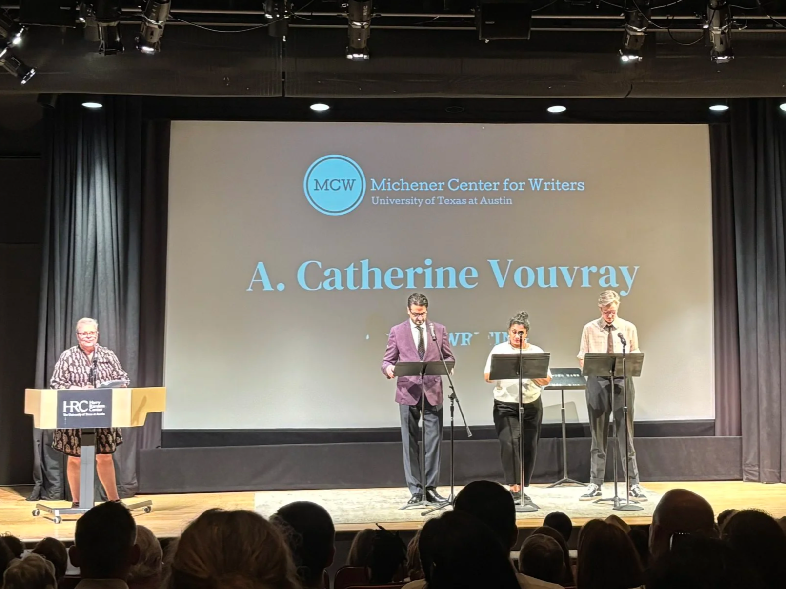 Me at podium with three actors in front of a screen with the Michener Center logo and my name with Screenwriting underneath