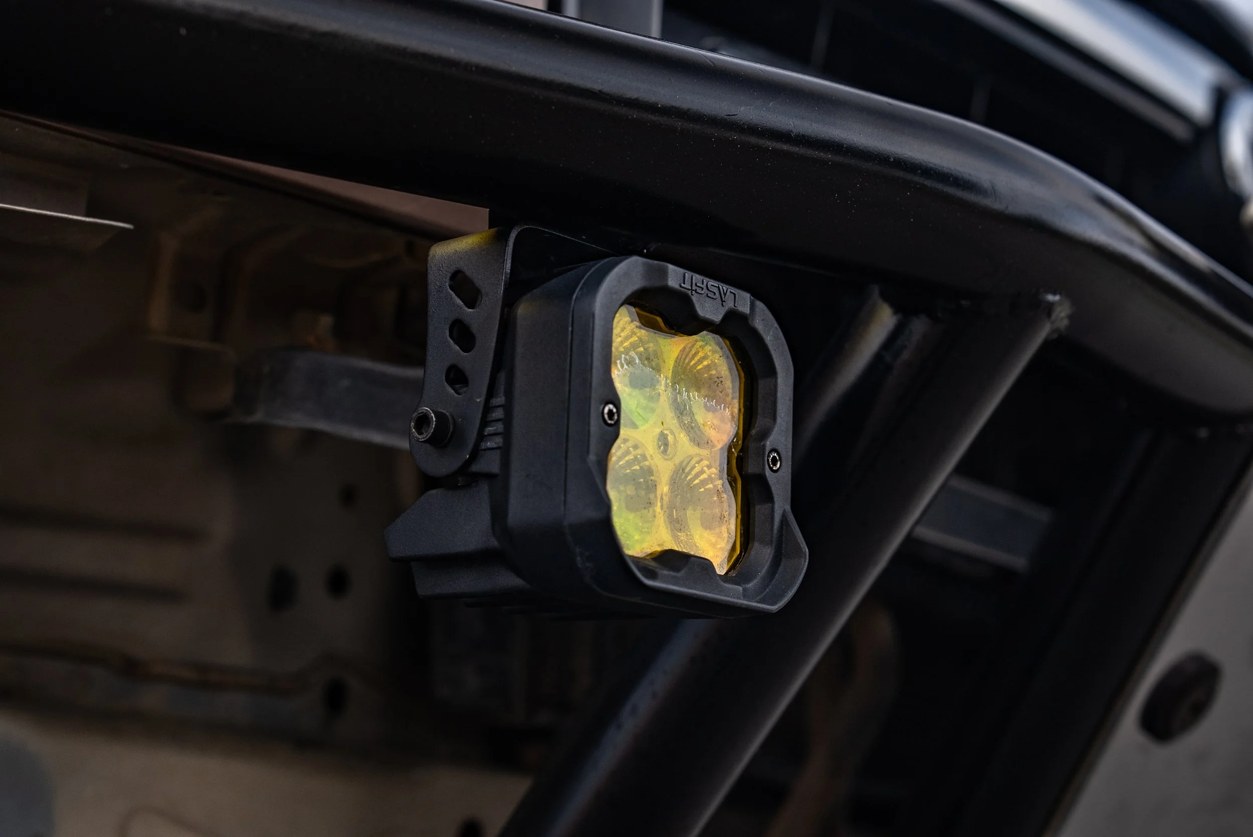 Close-up of a mounted LED off-road light attached to the underside of a vehicle's front bumper.