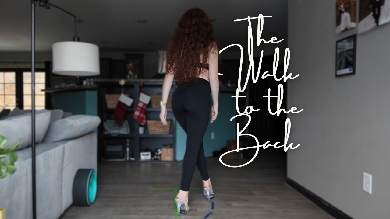 A woman with long curly hair walking away in a living room with a gray sofa, wall art, and a kitchen in the background, with text overlay that says 'The Walk to the Back'.