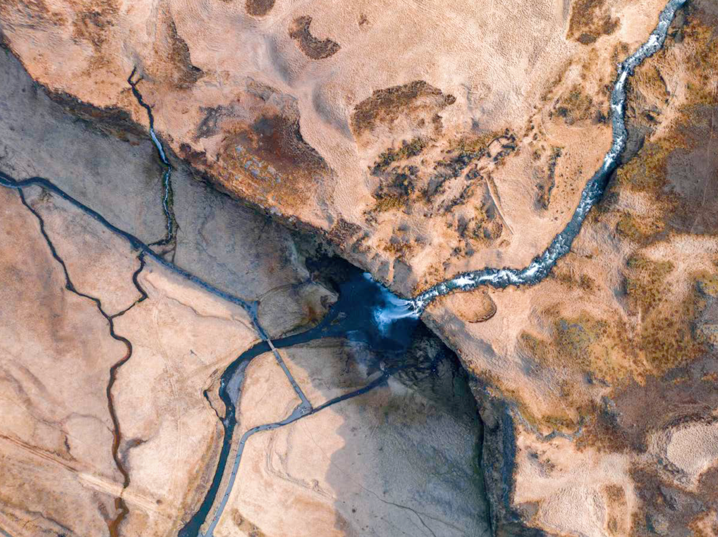 An aerial view of a desert landscape with a winding river cutting through the terrain.
