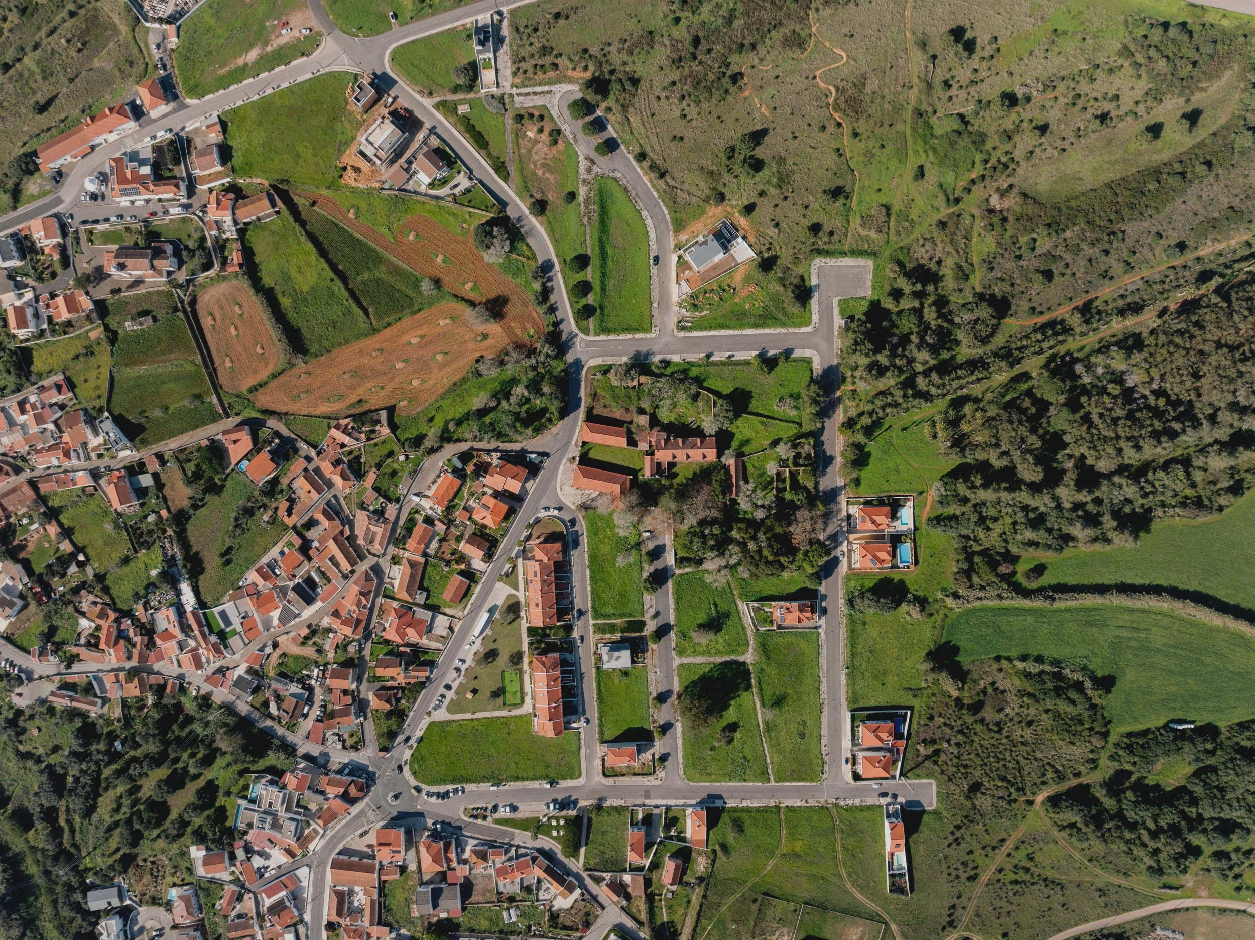 An aerial view of a residential neighborhood with houses, roads, and green fields.