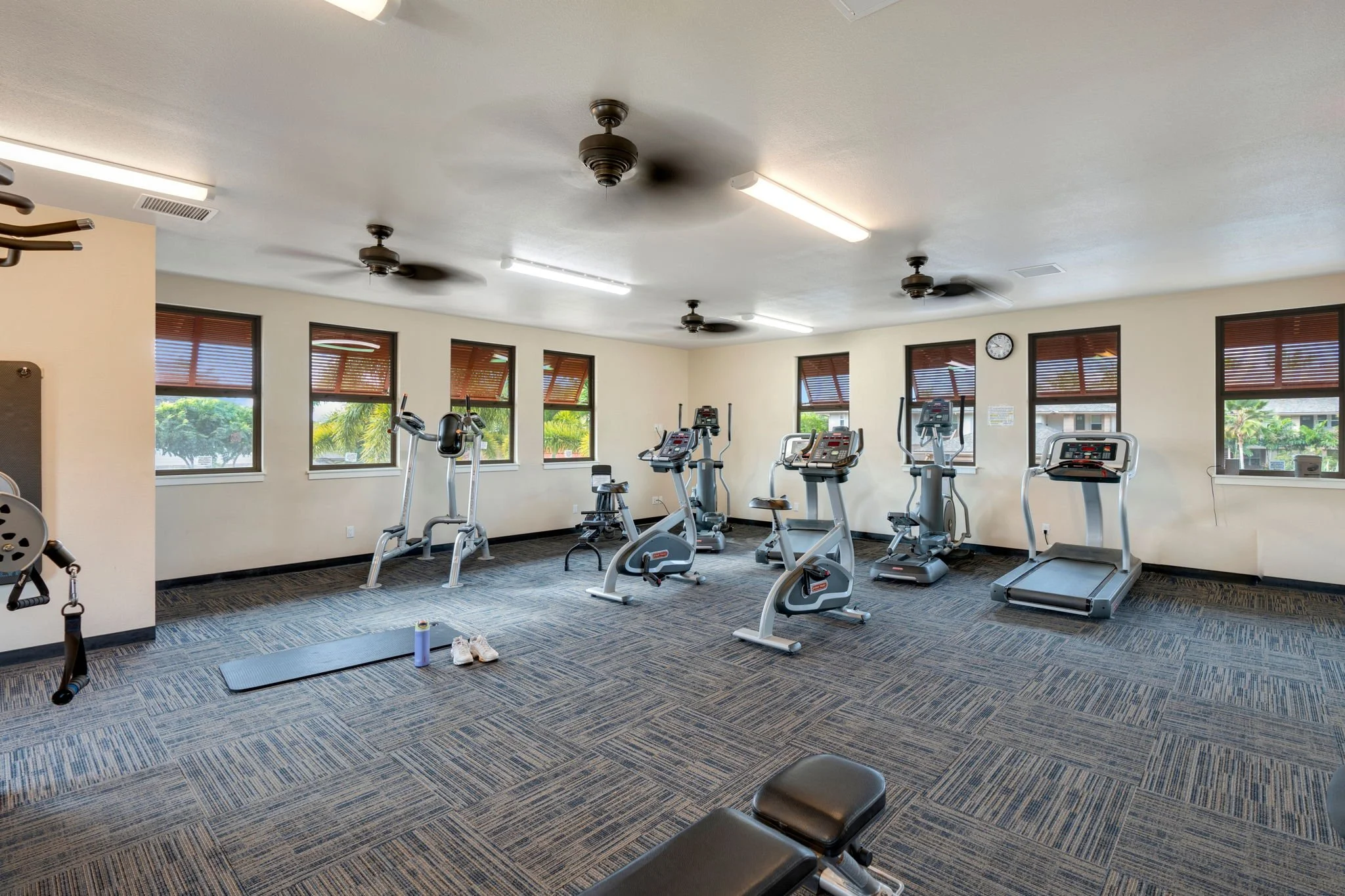 Indoor fitness center with cardio machines and ceiling fans