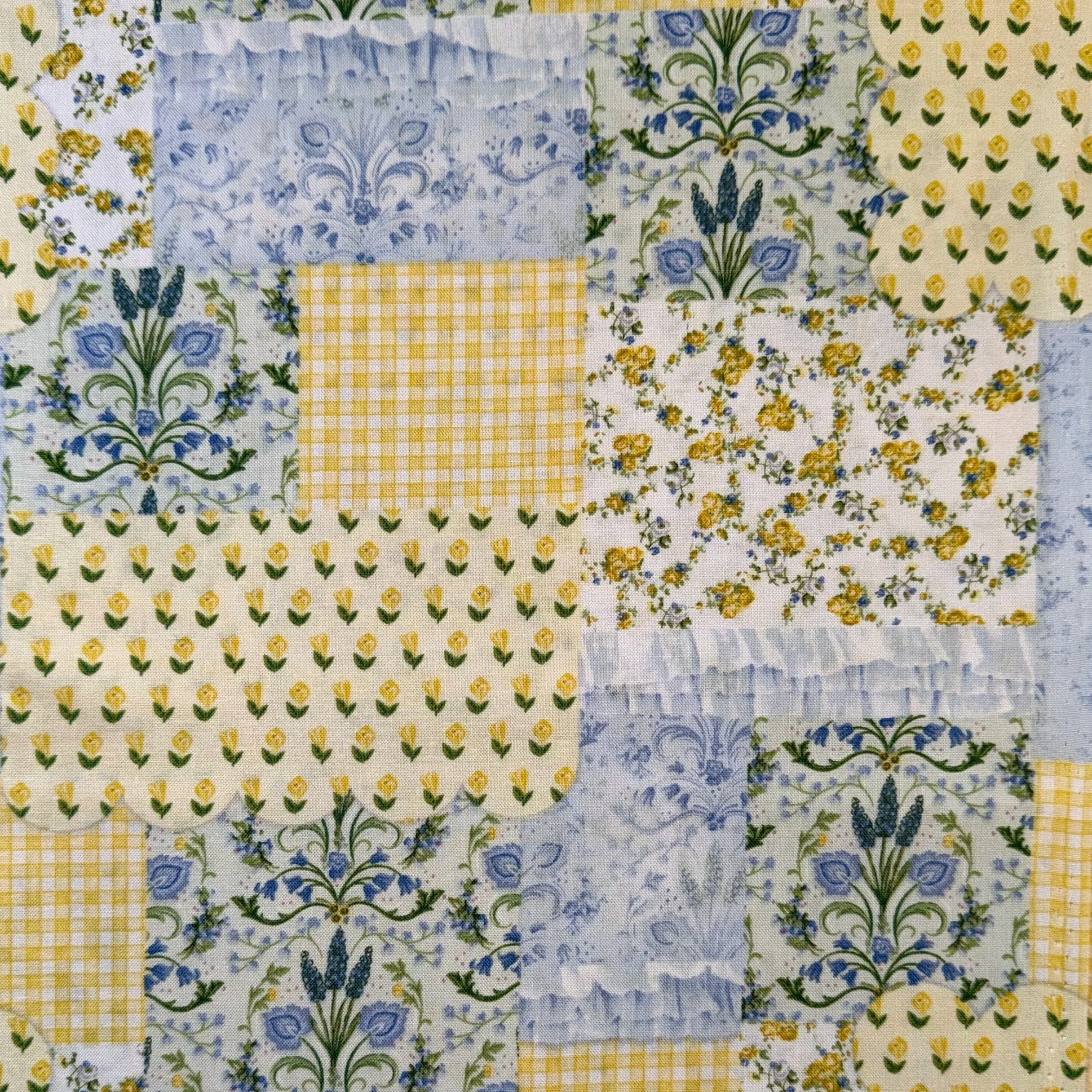Close-up of a patchwork quilt with yellow and blue floral patterns and checkered designs.