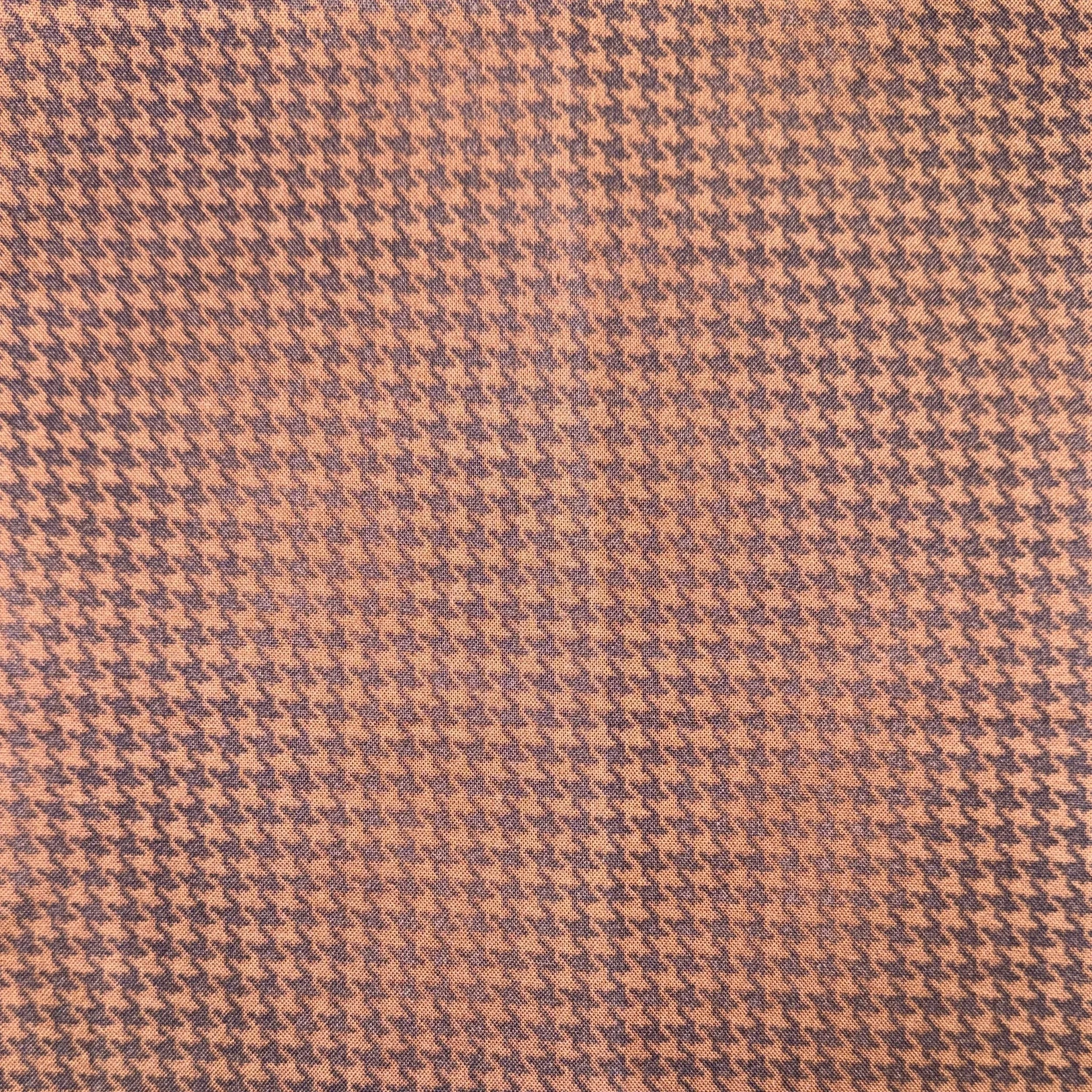 Close-up of a fabric with a houndstooth pattern in shades of pink and purple.