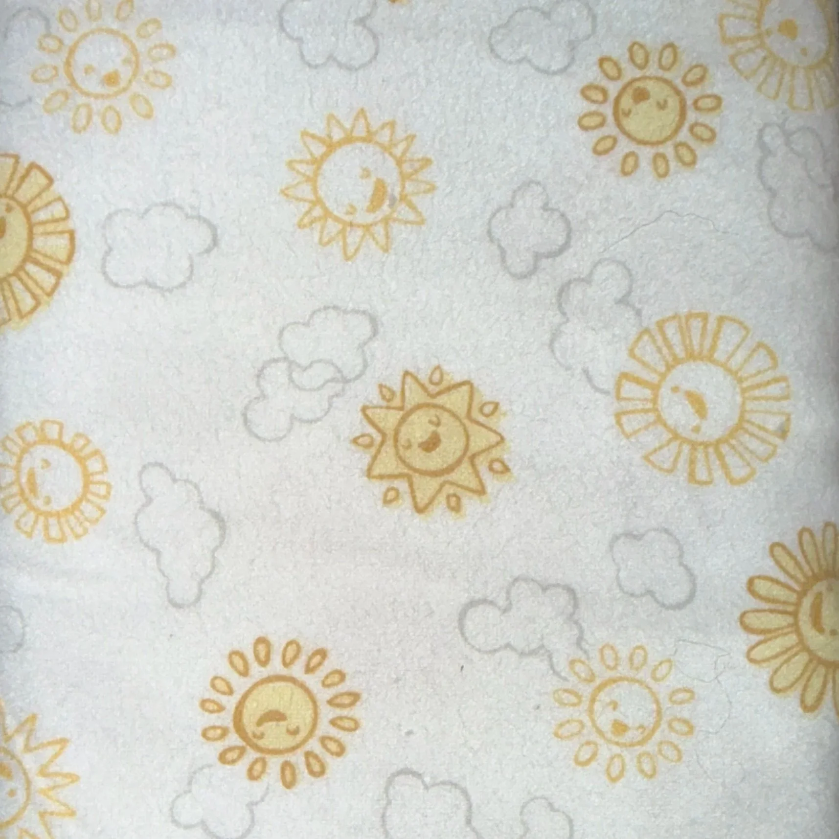 Pattern of yellow and orange smiling suns and gray clouds on a white background.