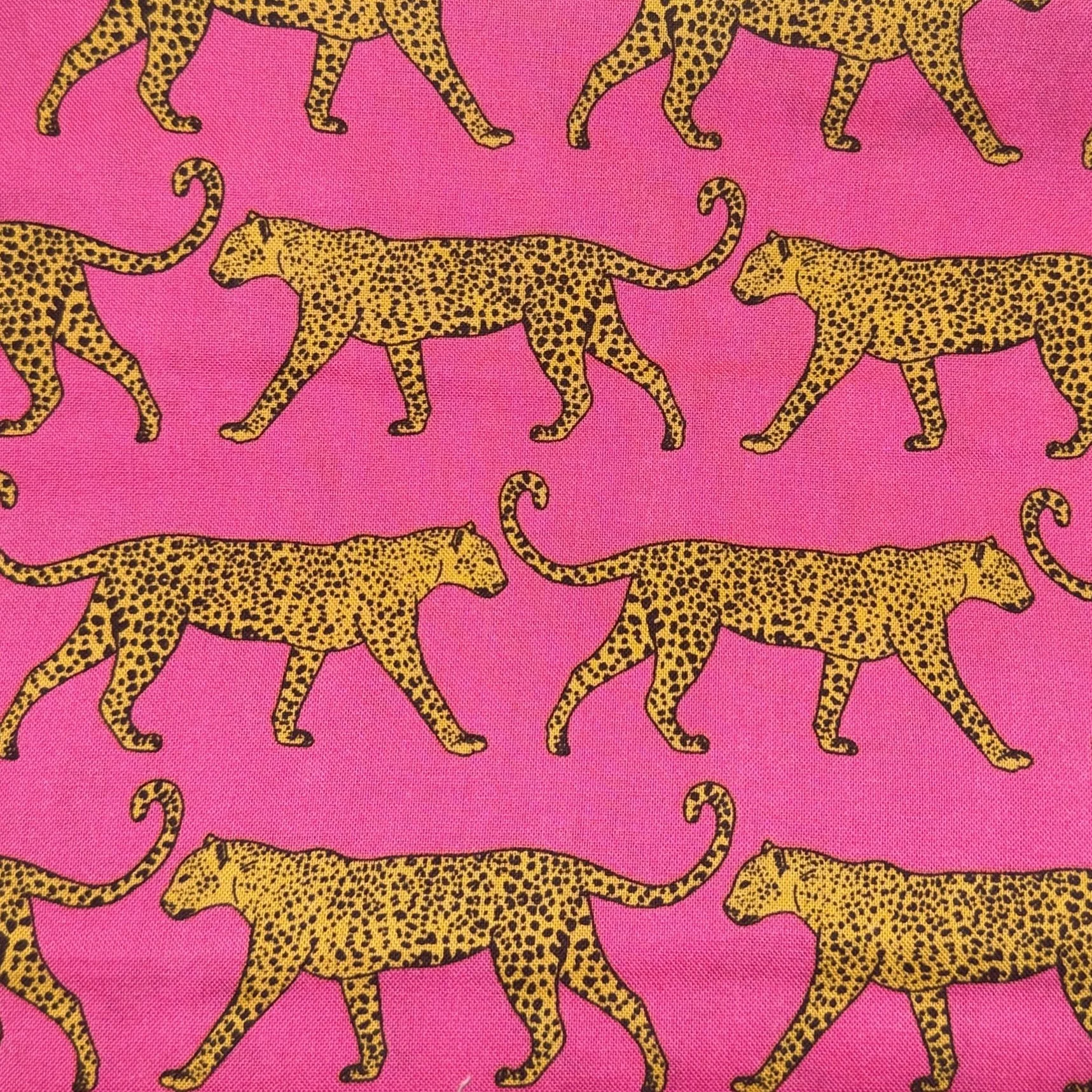 Pattern of yellow leopards with black spots walking on a pink background.