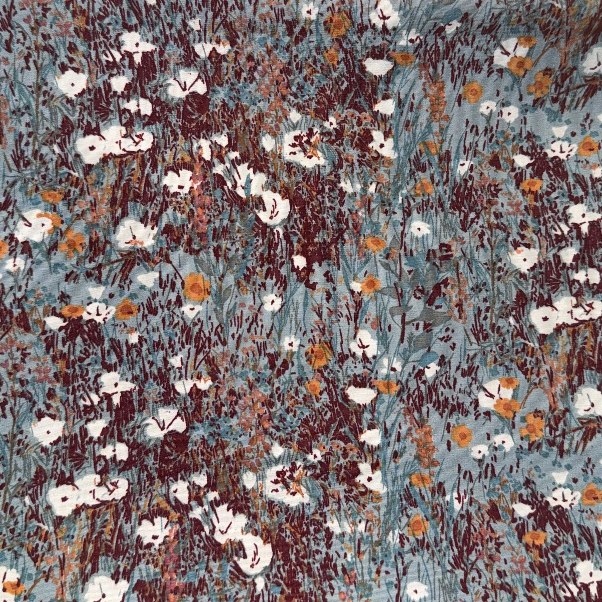 Close-up view of a floral fabric pattern with small white and orange flowers on a light blue background.