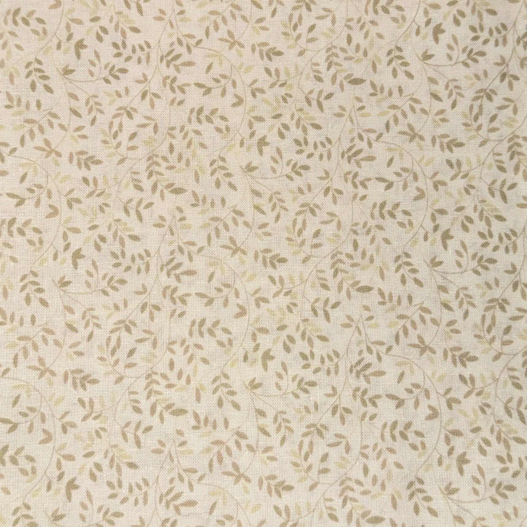 Close-up of beige fabric with a small floral leaf pattern woven in, in light brown and cream colors.