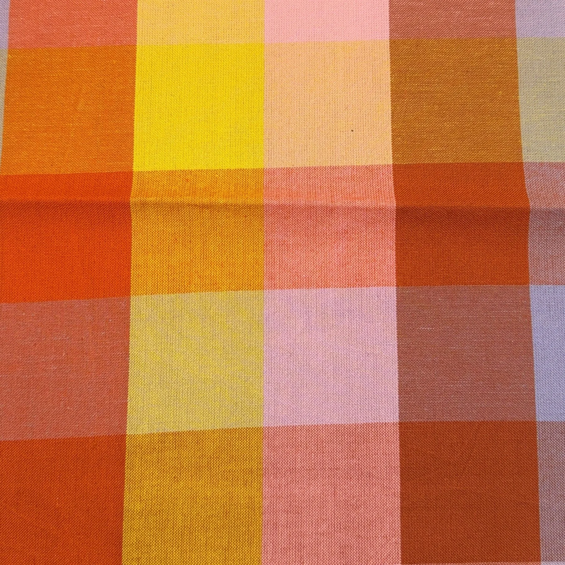 Close-up of a colorful plaid fabric with red, yellow, pink, and orange squares.