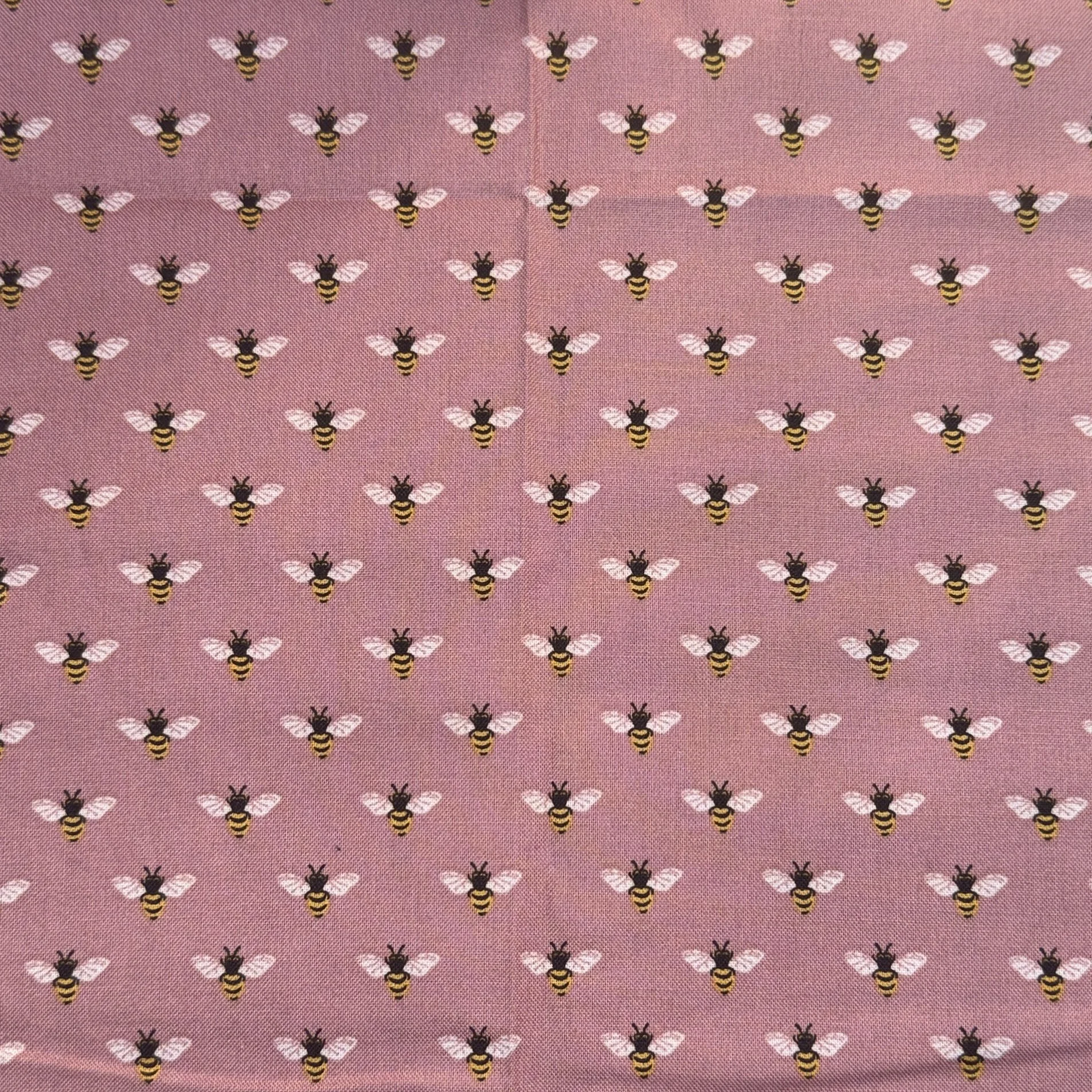 Pink fabric with small repeating bee pattern.