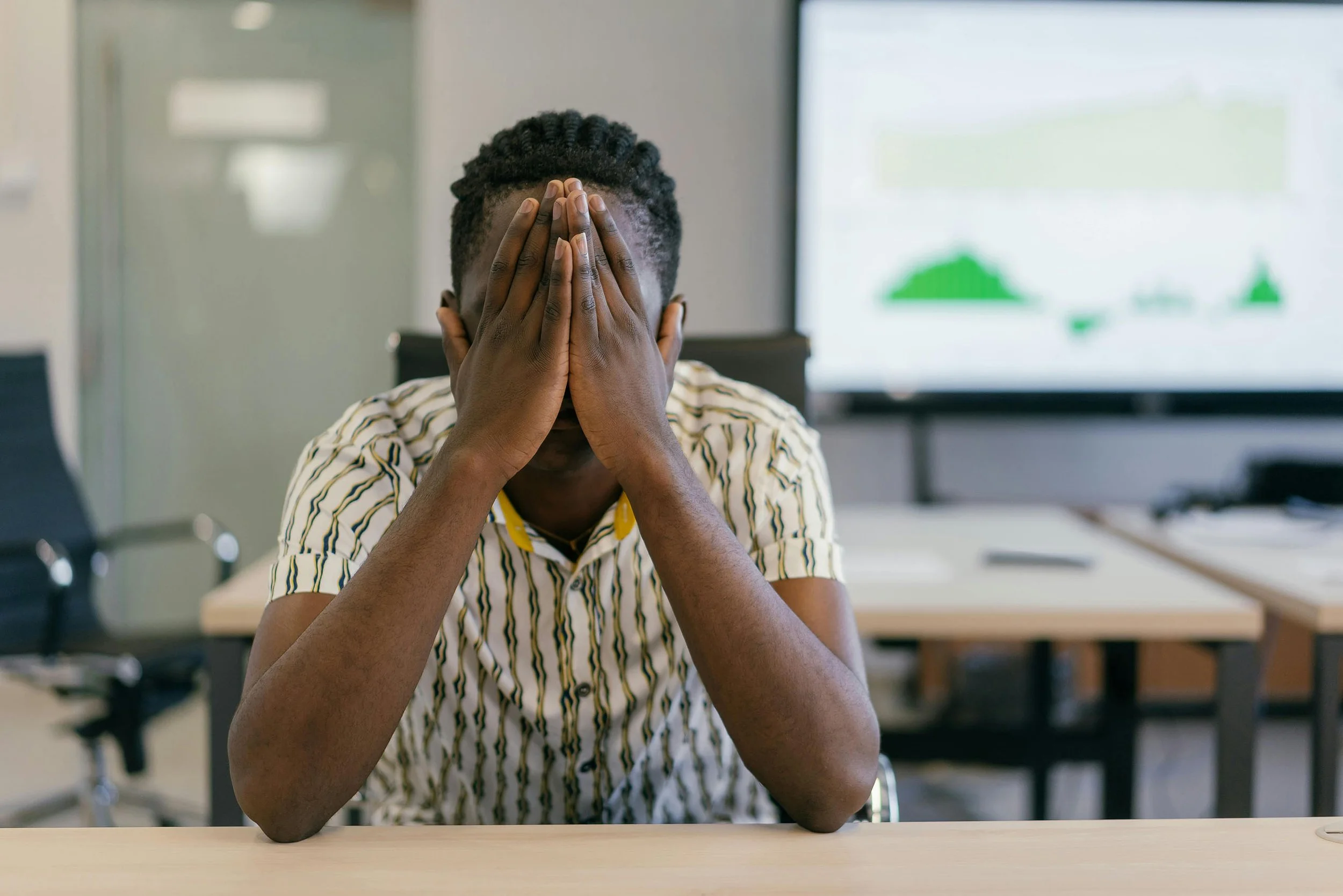Teen sitting at a desk with their face in their hands
