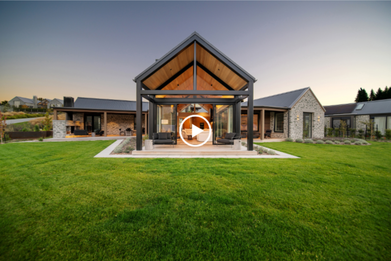 Modern house with a large front yard, screened porch, and steep roof, during sunset