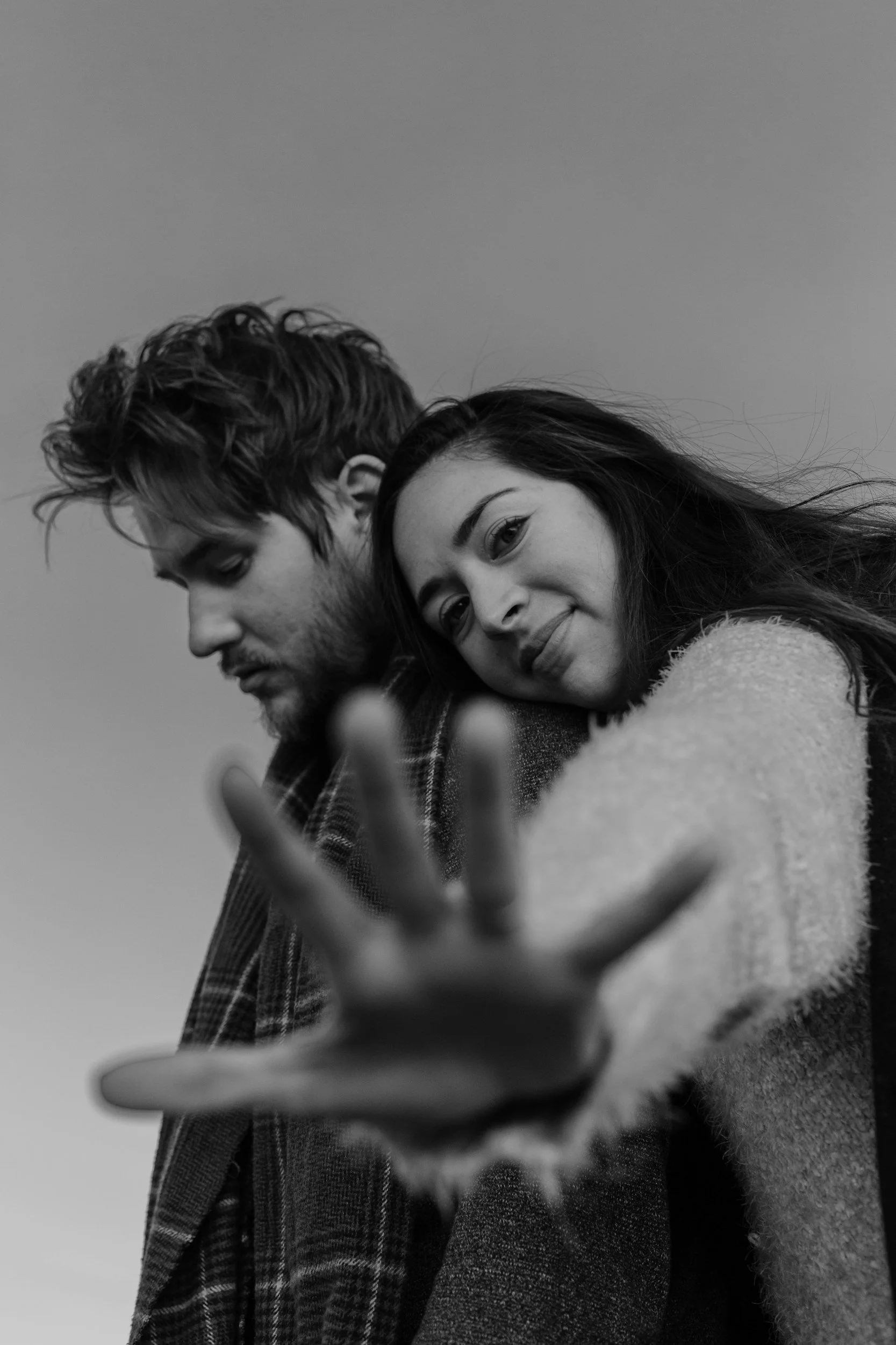 Black and white photo of a couple leaning on each other, with the woman reaching forward, representing connection and emotional vulnerability.