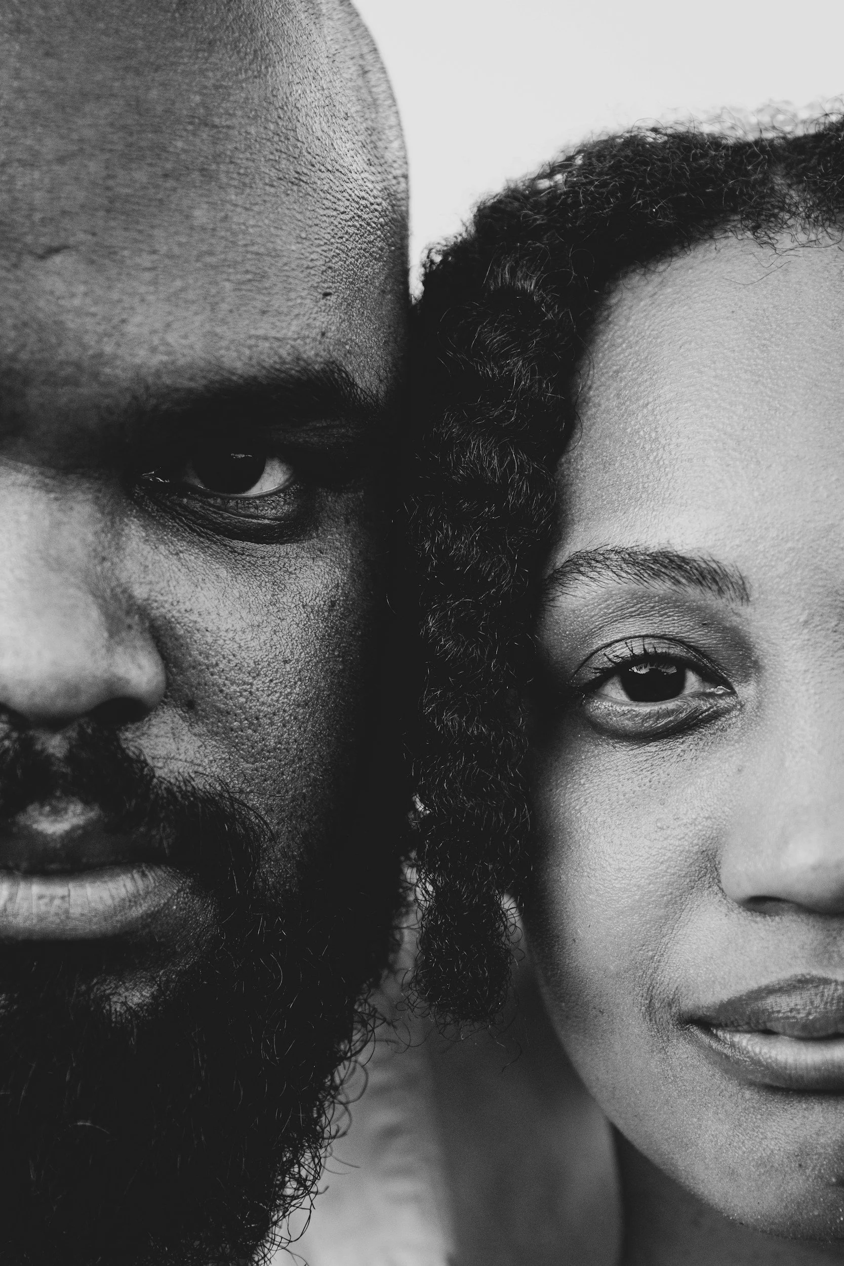 Black and white close-up portrait of two people side by side, highlighting presence, connection, and emotional closeness.