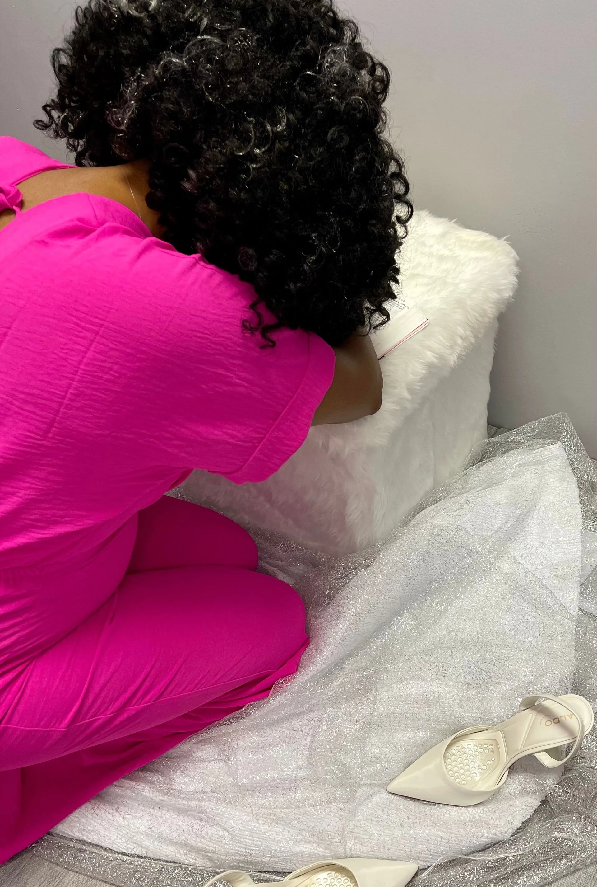 Sheenayvonne kneeling on the white square stool, praying in the bible.