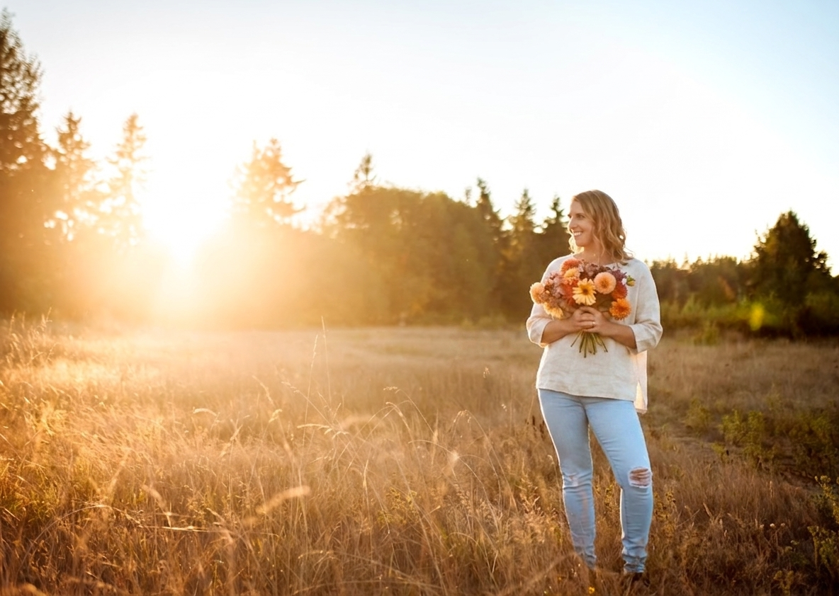 Alyson holding a bouquet of flowers in a sunlit field