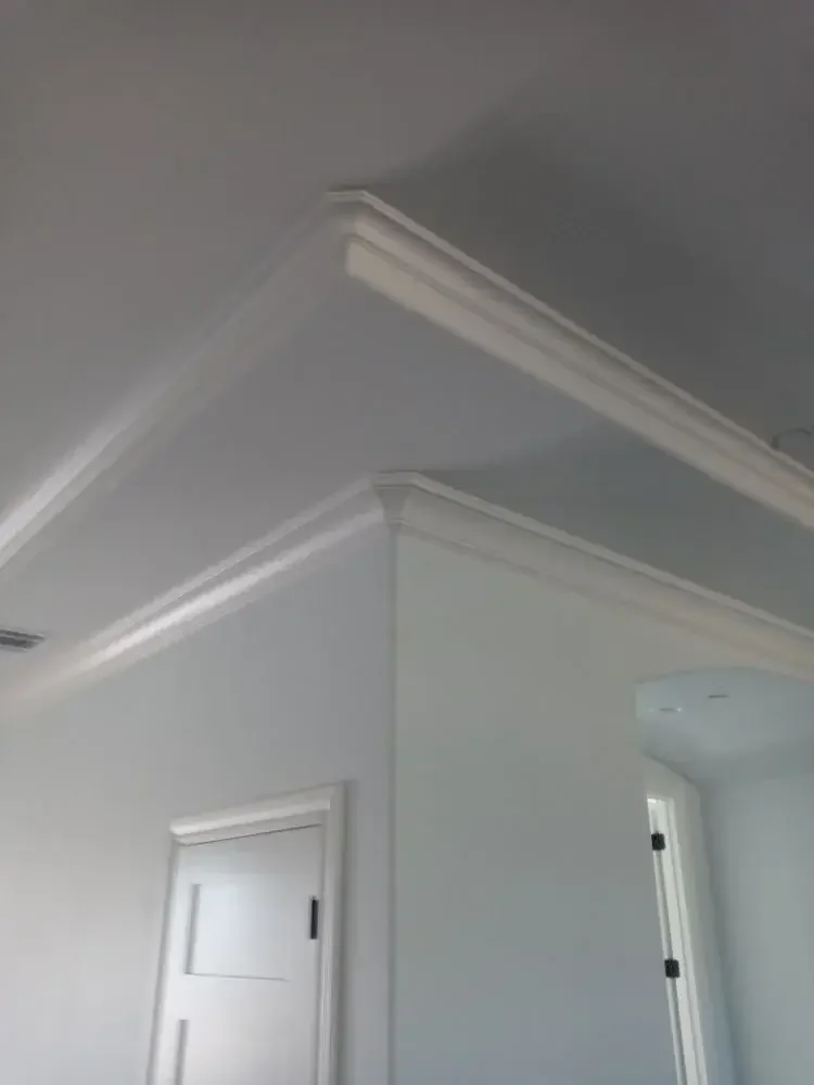 Custom white crown molding installation providing a clean and elegant transition between walls and ceiling in a residential home