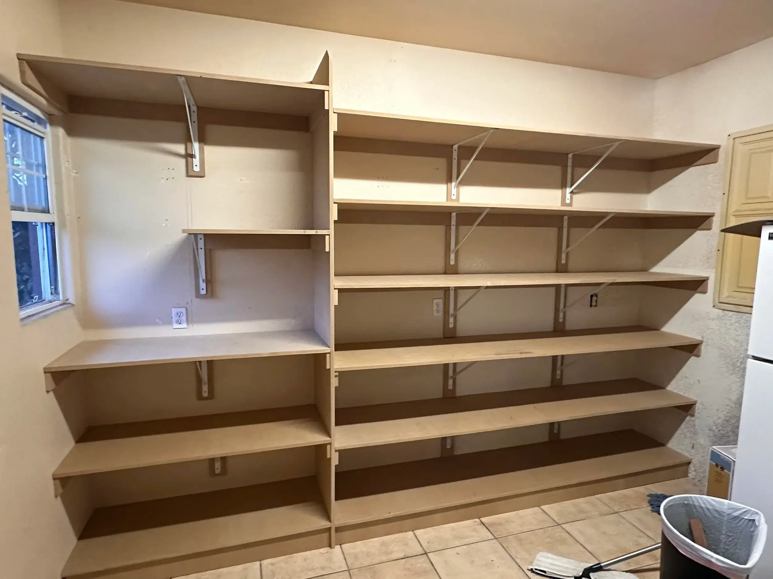 Custom wall-to-wall storage shelving installation providing organized storage and workspace solutions in a residential utility room.