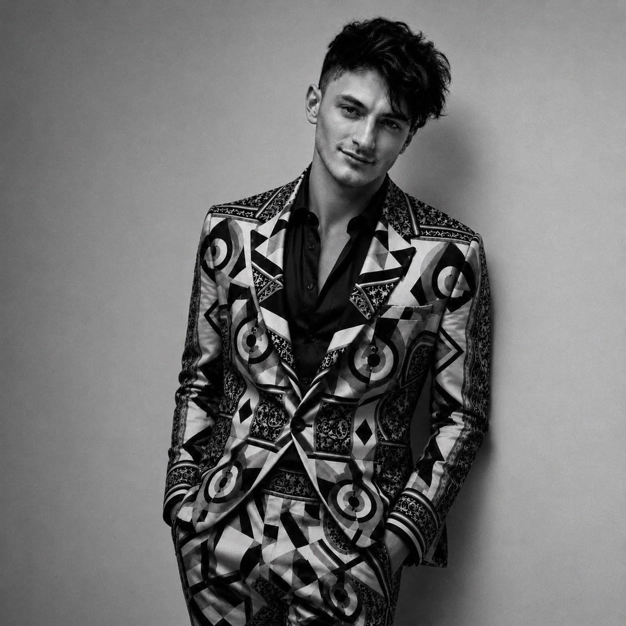 Black-and-white portrait of Zac Schurman in a geometric-patterned suit