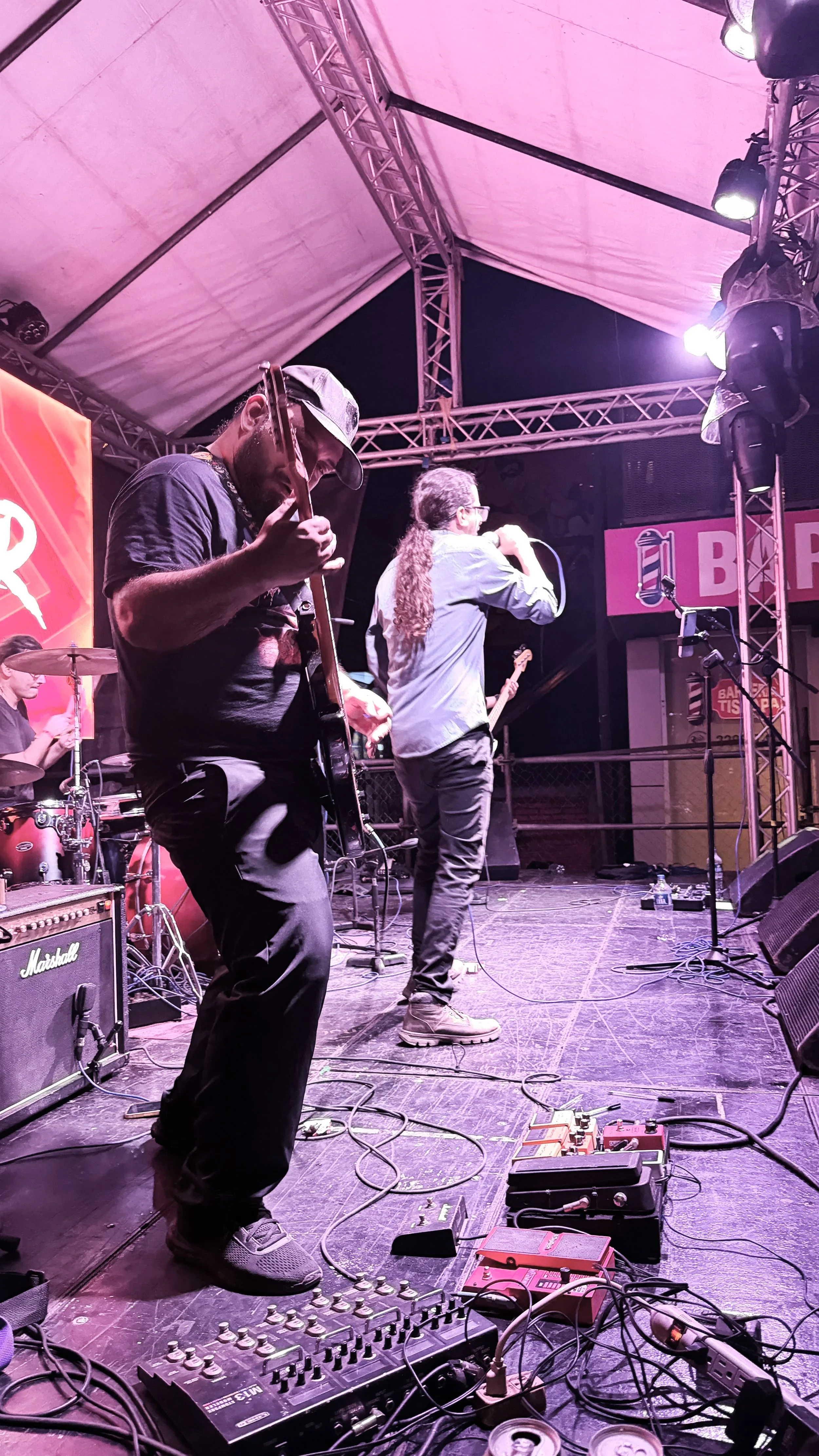 Band performing on stage with musical instruments and equipment at an outdoor concert.