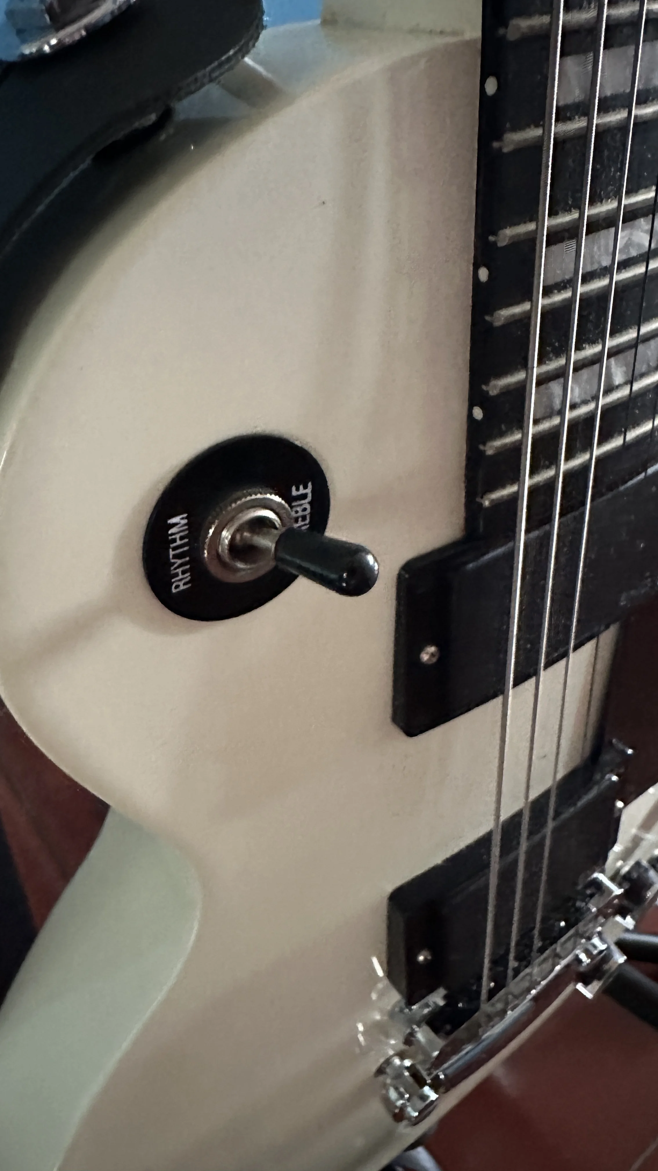 Close-up of an electric guitar's control knob and part of the fretboard with strings.