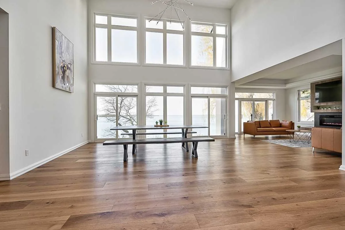 Spacious living room with large windows, a dining table, and a seating area with sofas and a fireplace.
