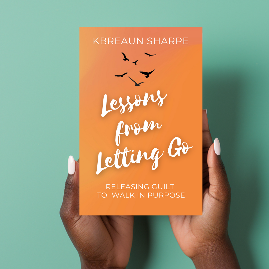 Book cover titled 'Lessons from Letting Go' by KBrean Sharpe, with black bird silhouettes and orange background, held by a person with dark skin and white nail polish against a green backdrop.
