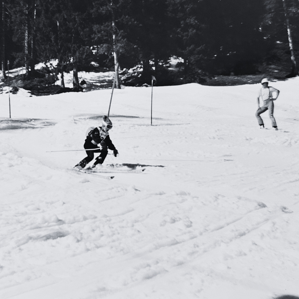 Enfant skiant sur une piste enneigée, avec des montagnes et des arbres en arrière-plan.