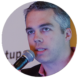 Clay Hebert speaking into a microphone at an event or conference.