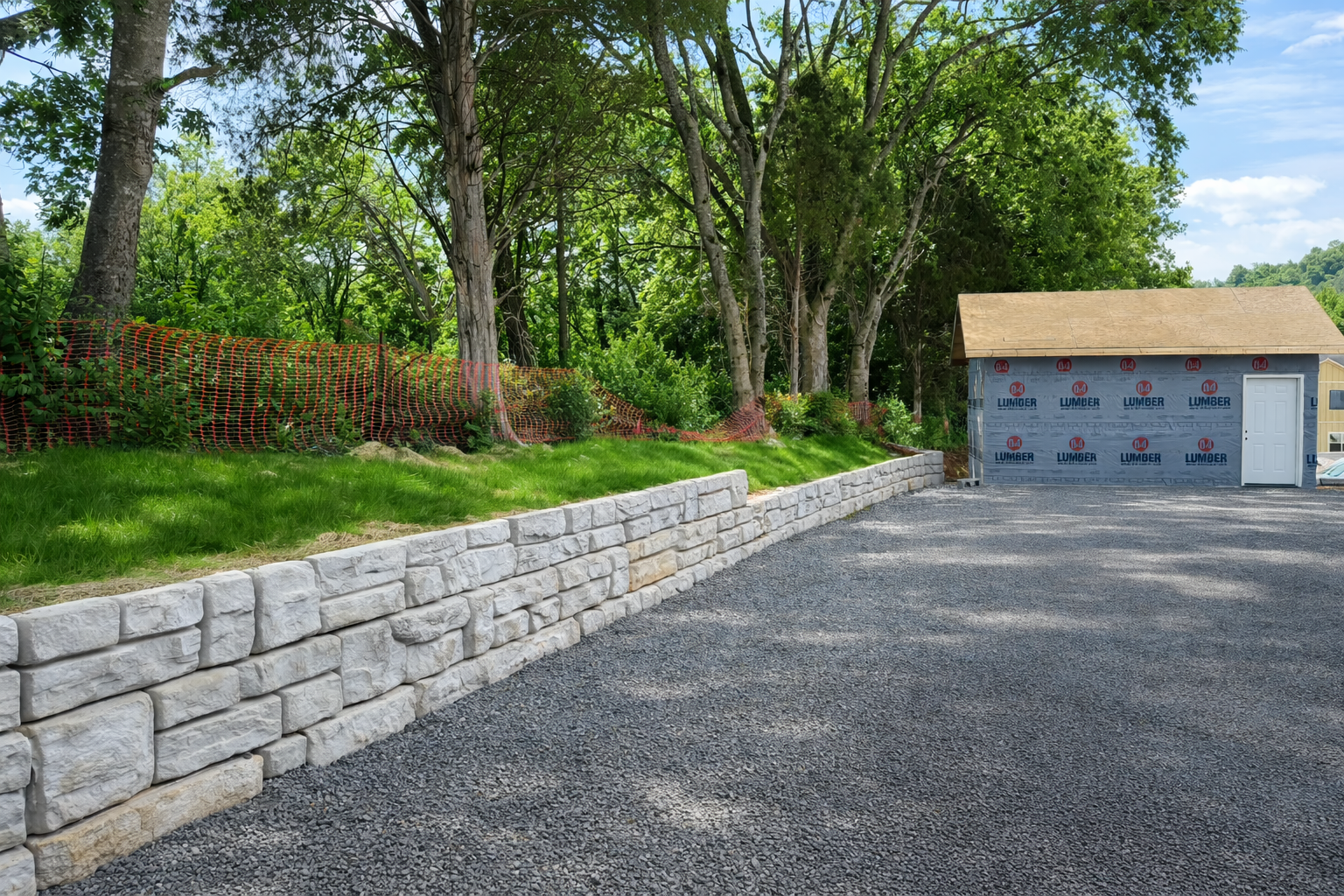 Stone retaining wall and gravel driveway installation in Sevierville TN with landscaped yard