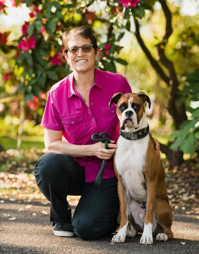 Marcia and her boxer Chago in front of floral tree