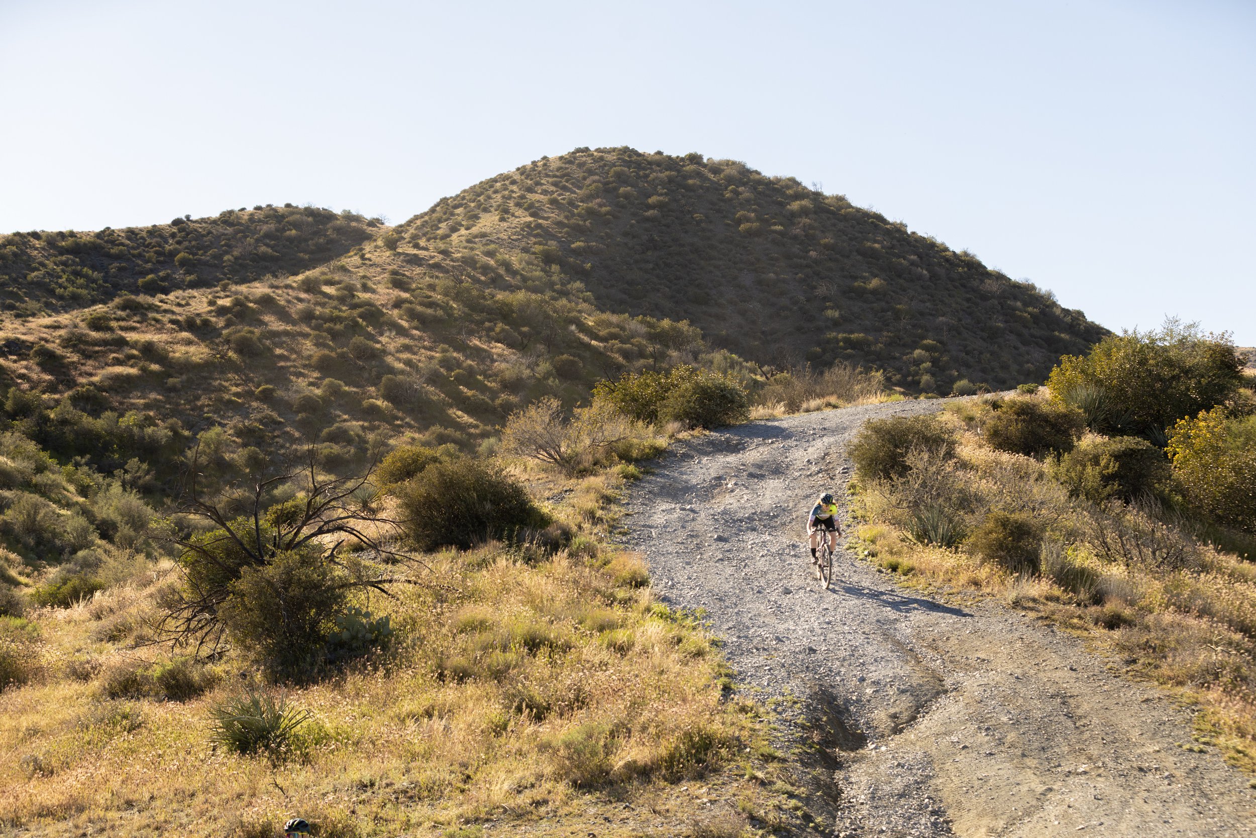 bike rider going downhill on gravel road in the desert