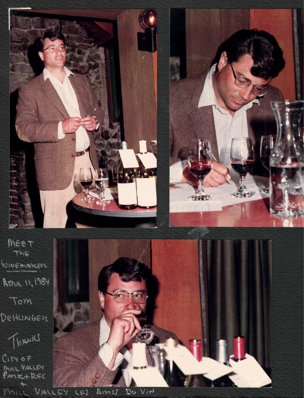 A man in a brown blazer and glasses participating in a wine tasting event, with bottles of wine, glasses, and tasting notes on a table. The setting appears to be indoors with a stone wall background.