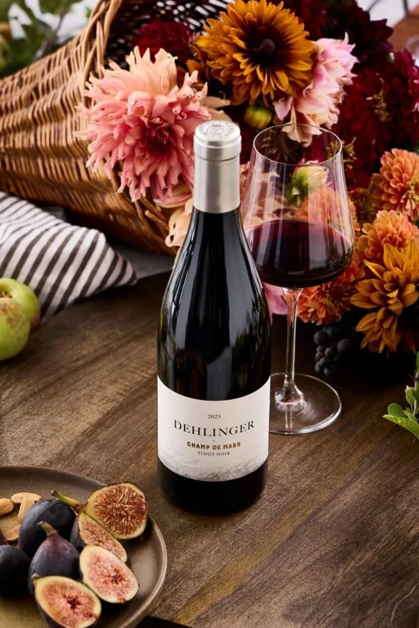 A bottle of 2023 Champ de Mars Pinot noir from Dehlinger surrounded by flowers and figs
