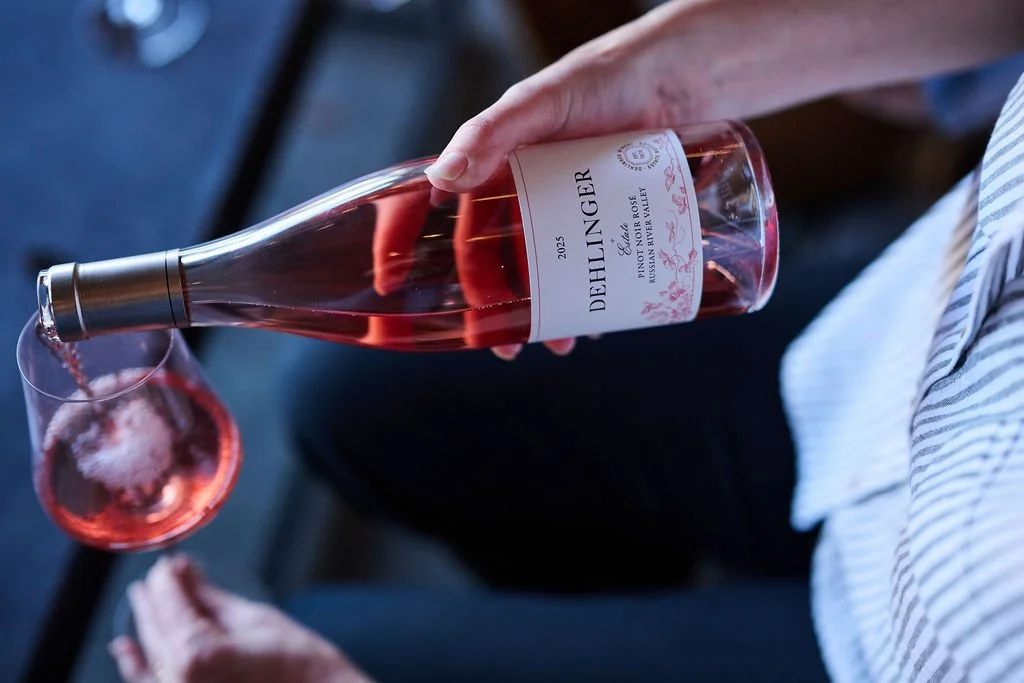 A hand pouring a bottle of Dehlinger Rose wine