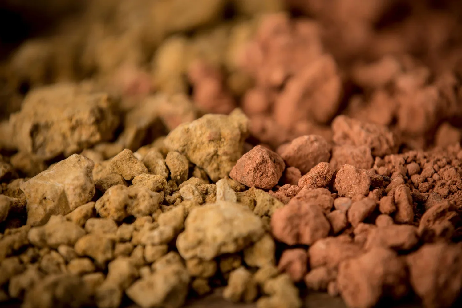 Close-up of colorful crushed minerals or rocks in yellow, pink, and brown hues.