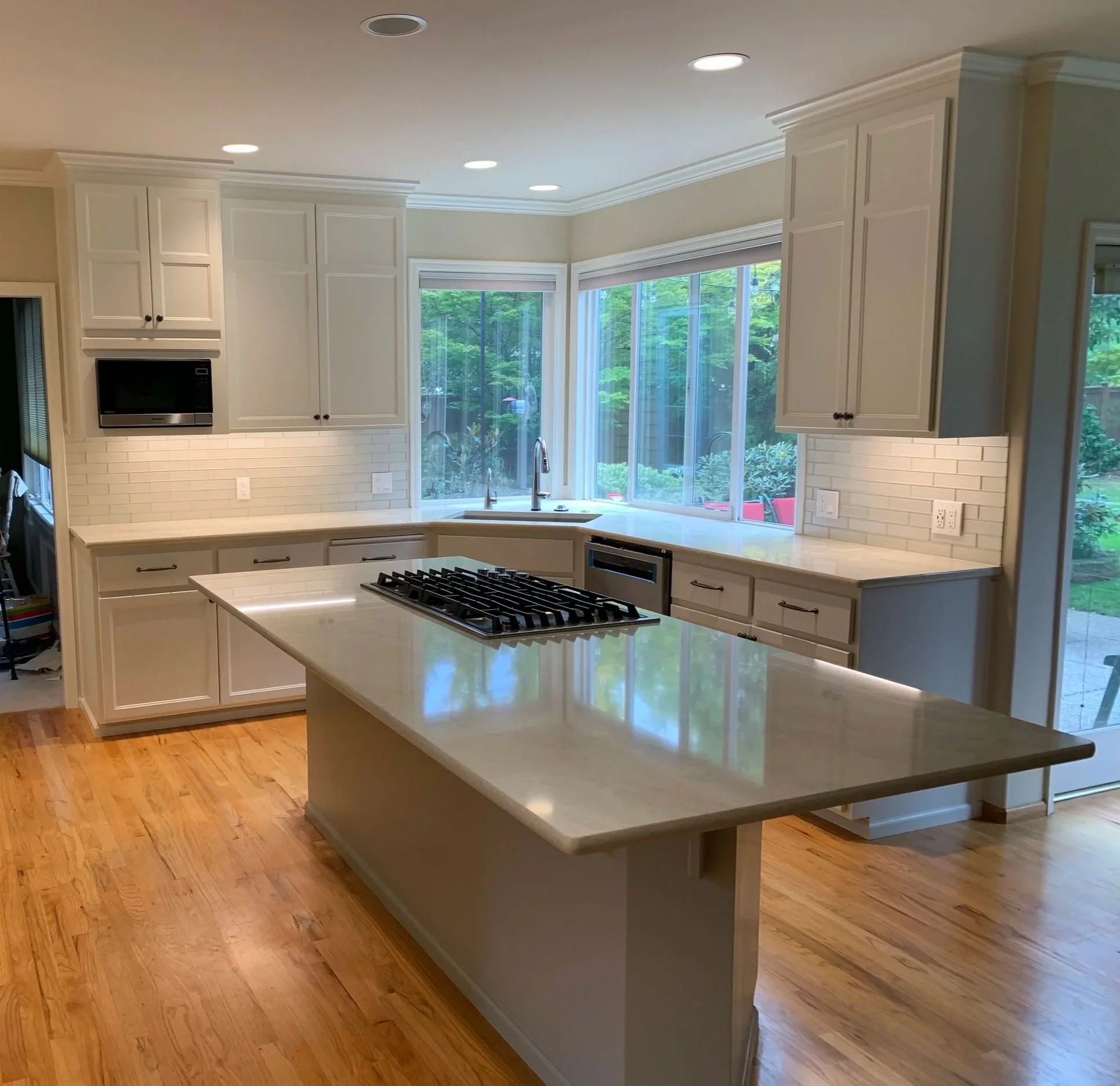 Modern kitchen with white cabinets, marble countertops.