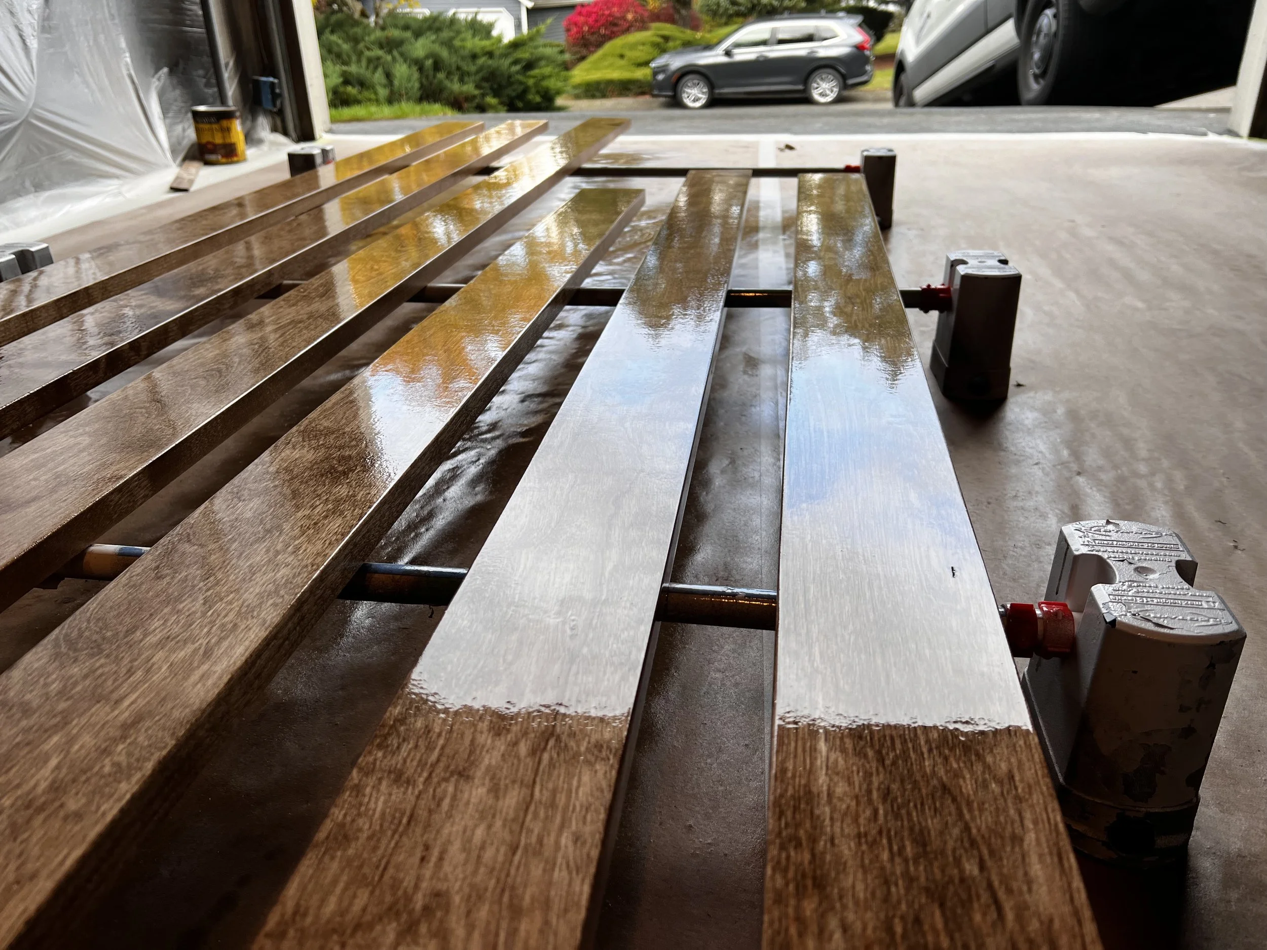 Wooden planks on a workbench in a garage, drying after being varnished.