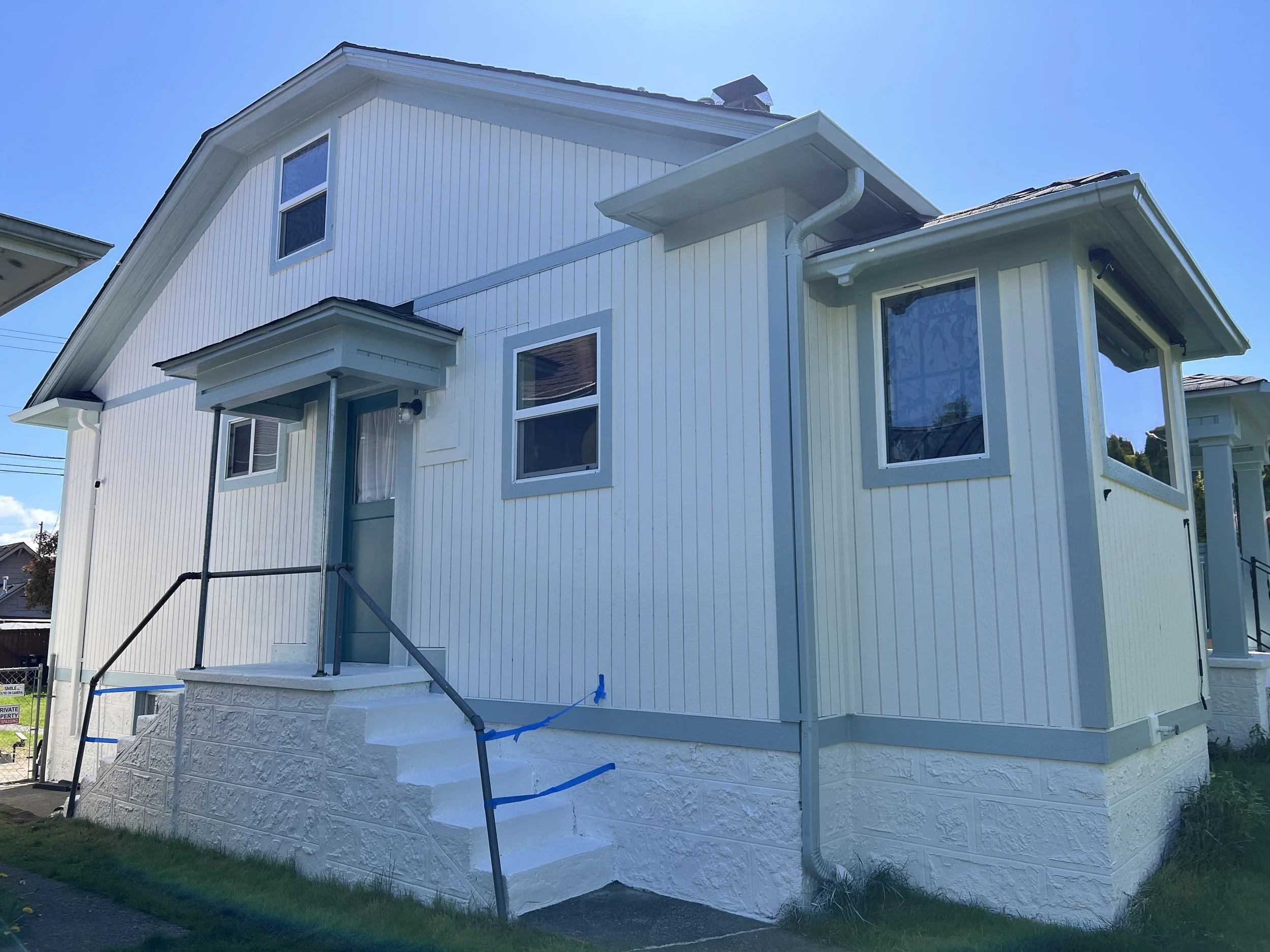 White two-story house with gray trim, front steps, and a front porch.