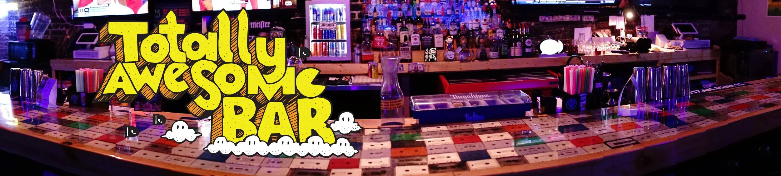 A colorful bar with a tiled counter and various bottles and bar accessories behind it. Overlay text reads "Totally Awesome Bar" with cartoon clouds and playful font.