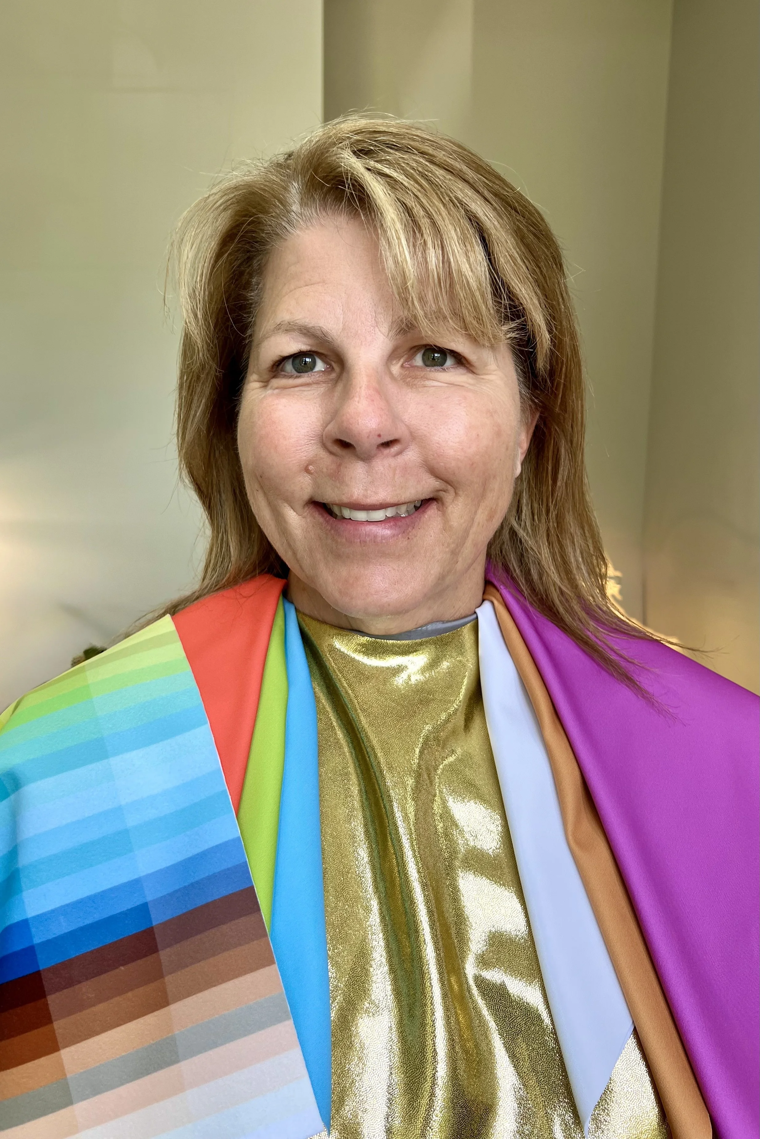 A woman with light brown hair smiling, wearing her Classic Spring color analysis drapes from a consultation at Unveiled Hue in Williamsburg/Newport News/Hampton area of Virginia.