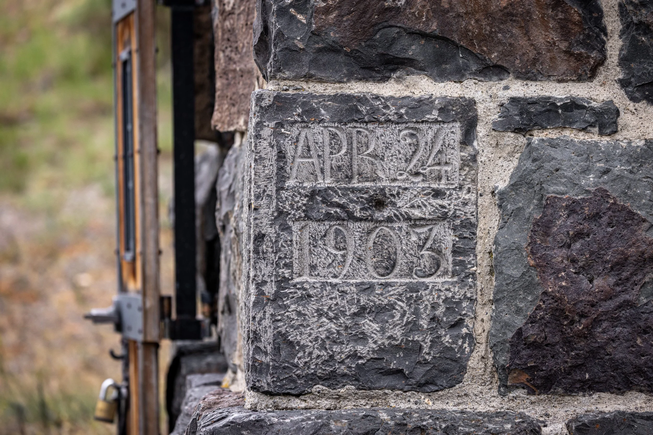 A close-up detail shot of the weathered stone masonry and inscribed block of the historic Roosevelt Arch entry.