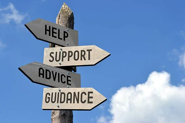 Signpost with four arrows labeled 'Help,' 'Support,' 'Advice,' and 'Guidance' against a blue sky with clouds. help, support, guidance, health, care, kara cares.