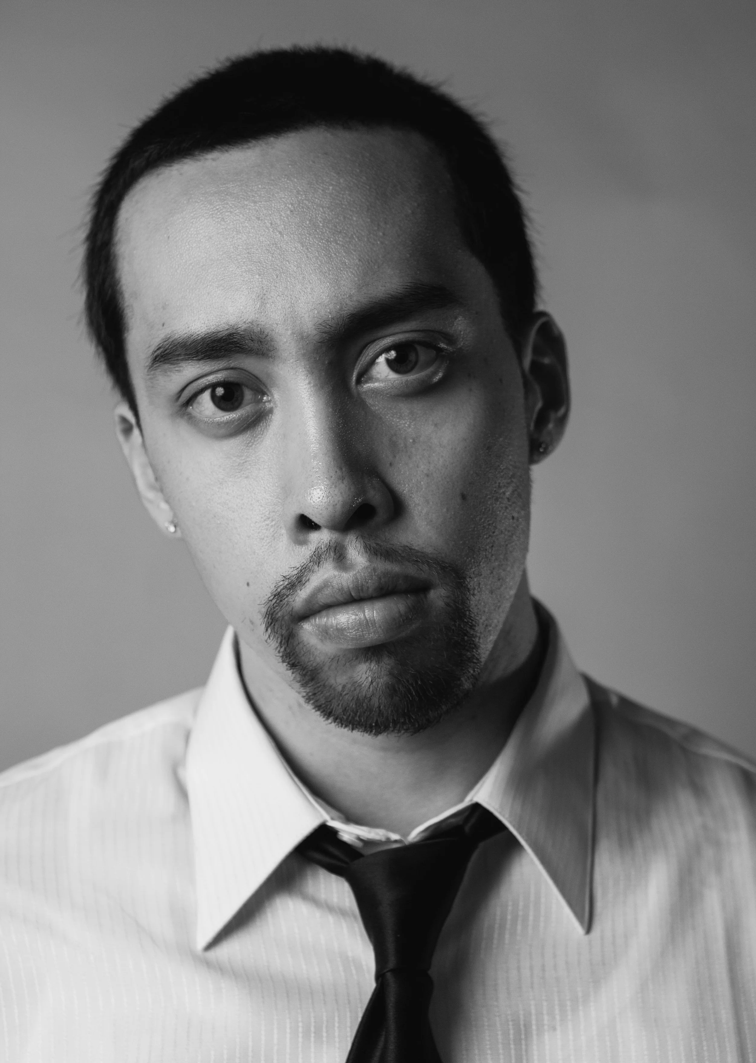 Black and white portrait of a young man with short hair, wearing a light-colored collared shirt and a dark tie.