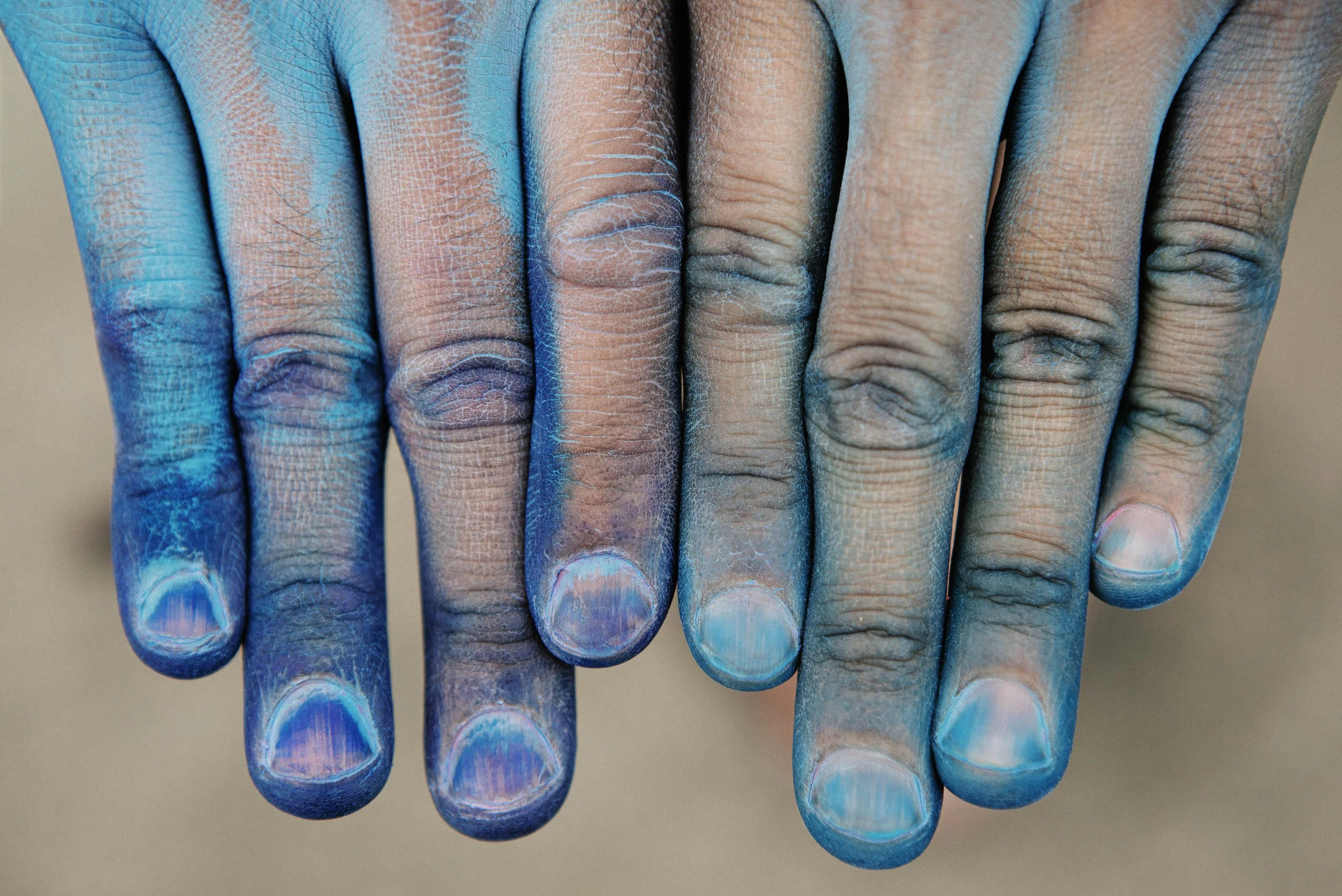 Close-up of fingers painted in shades of blue, with visible textures and details of the skin.