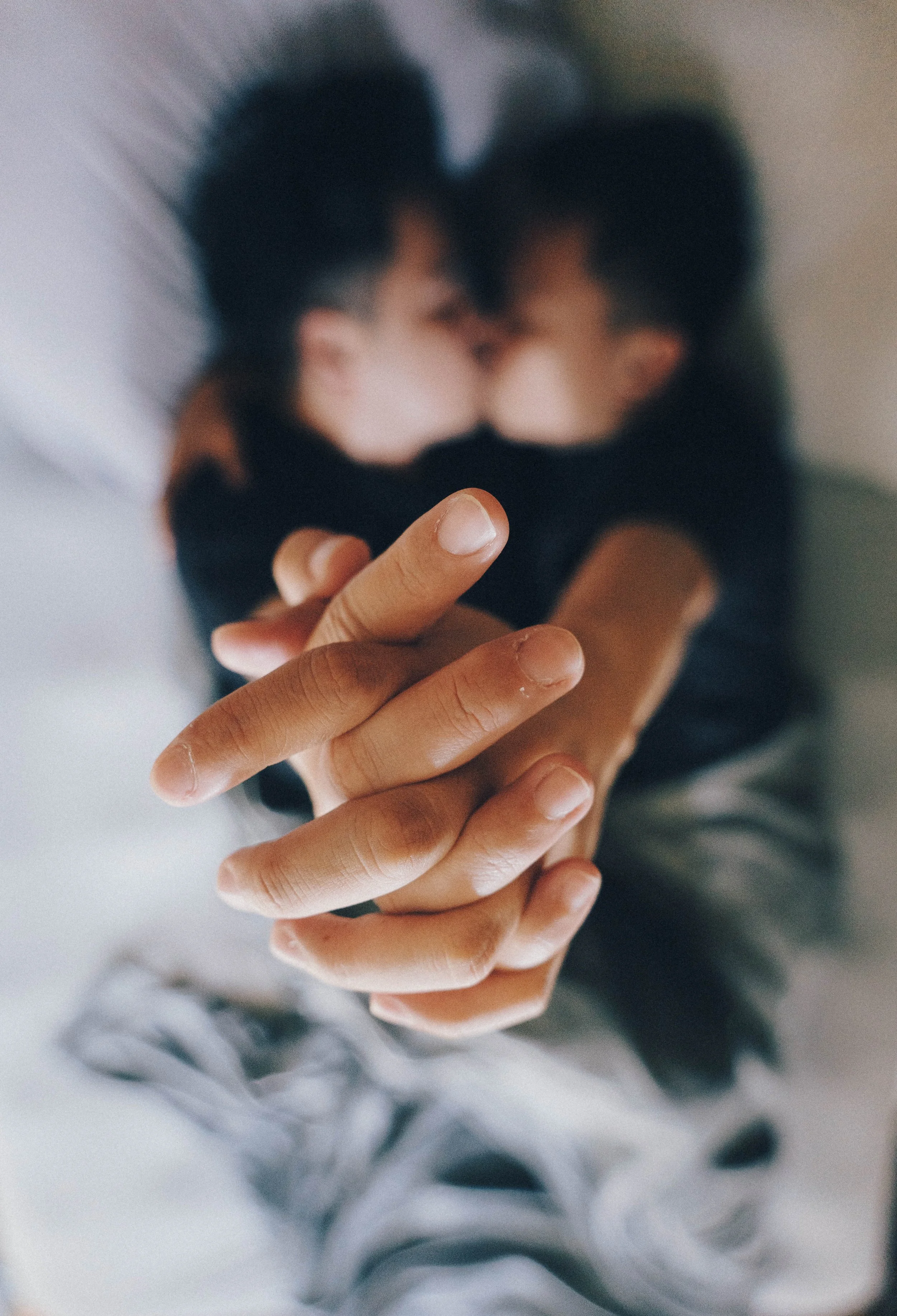 A person's hand holding a smartphone, showing a blurred image of two people kissing, with the focus on the hand and phone.